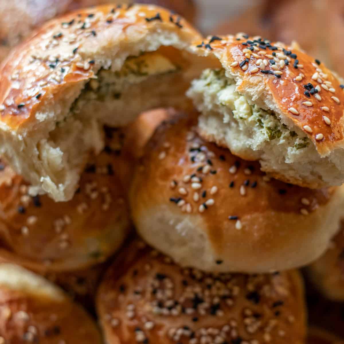 Golden brown Turkish pogaca buns filled with feta and parsley, cooling on a wire rack