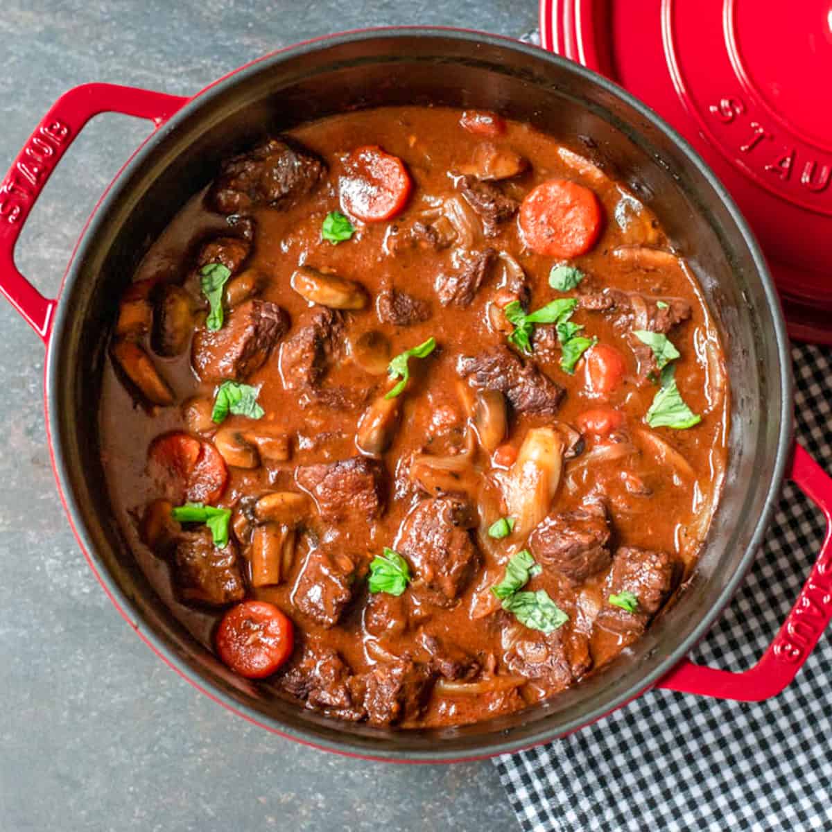 Julia Child's Beef Bourguignon Recipe served in a red Dutch oven.