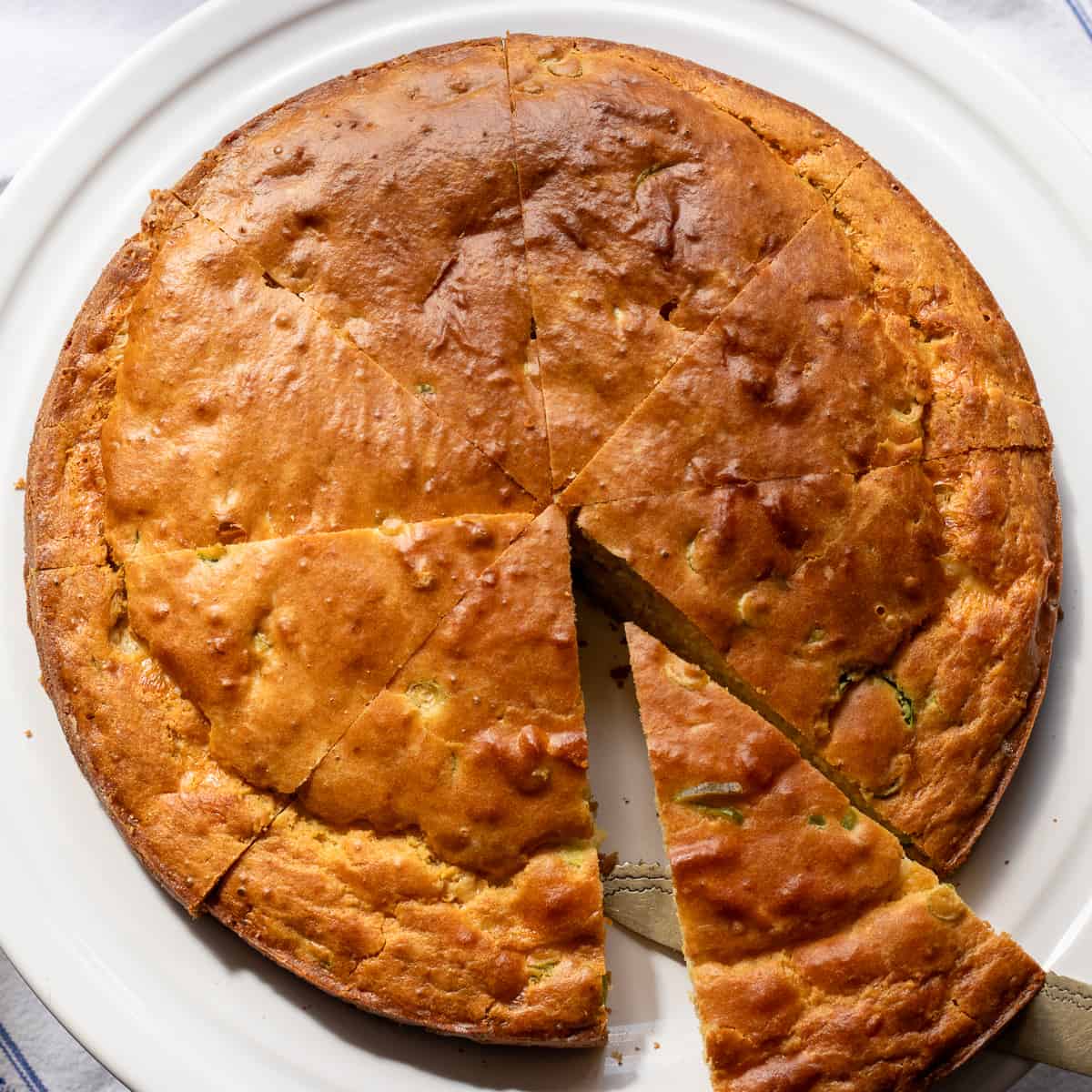 Mexican cornbread served on a plate, garnished with fresh green onions.
