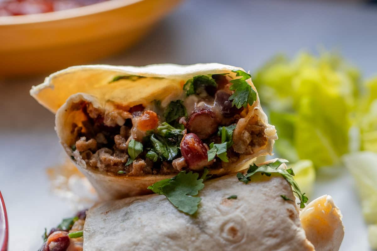 Mexican beef burrito cut in half, showing the beef filling